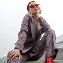 Mujer en un traje elegante y zapatos rojos, sentada en los escalones, emanando confianza y estilo.