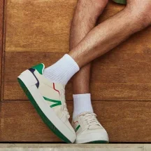 Hombre usando tenis blancos con detalles verdes.